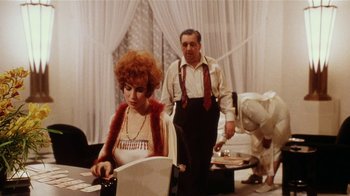 Movie still from “Bullets Over Broadway” (1994), directed by Woody Allen – A man and a woman are standing in front of a table; Medium shot, Over the shoulder angle