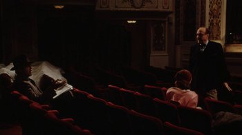 Movie still from “Bullets Over Broadway” (1994), directed by Woody Allen – A person sitting in an empty theater with red seats; Extreme Wide shot, High angle