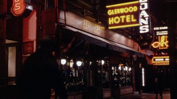 Movie still from “Bullets Over Broadway” (1994), directed by Woody Allen – A man is walking in front of a restaurant; Wide shot, High angle