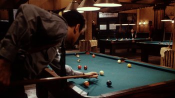 Movie still from “Bullets Over Broadway” (1994), directed by Woody Allen – A man is playing a game of billiards; Wide shot, Over the shoulder angle