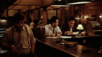 Movie still from “Bullets Over Broadway” (1994), directed by Woody Allen – A group of men sitting at a table in a restaurant; Medium shot, Over the shoulder angle