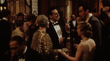 Movie still from “Bullets Over Broadway” (1994), directed by Woody Allen – A group of people standing in a room; Medium shot, Over the shoulder angle