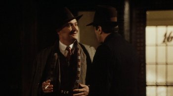 Movie still from “Bullets Over Broadway” (1994), directed by Woody Allen – A man in a suit and hat talking to another man in a suit and hat; Medium shot, Over the shoulder angle