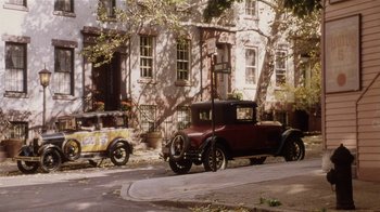 Movie still from “Bullets Over Broadway” (1994), directed by Woody Allen – An antique car parked on the side of the road; Extreme Wide shot, High angle
