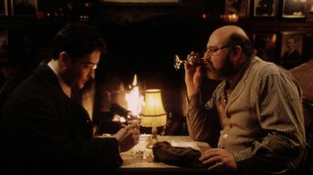 Movie still from “Bullets Over Broadway” (1994), directed by Woody Allen – Two men sitting at a dinner table drinking wine; Medium shot, Over the shoulder angle