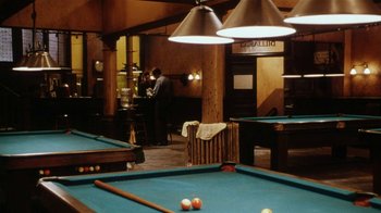 Movie still from “Bullets Over Broadway” (1994), directed by Woody Allen – A man is playing a game of billiards; Wide shot, High angle