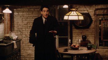 Movie still from “Bullets Over Broadway” (1994), directed by Woody Allen – A man standing in front of a table with a bowl on it; Medium shot, Low angle