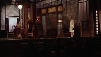 Movie still from “Bullets Over Broadway” (1994), directed by Woody Allen – A woman standing on a stage in front of an audience; Wide shot, Low angle