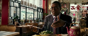 Movie still from “xXx: Return of Xander Cage” (2017), directed by D.J. Caruso – A man in a business suit is holding chopsticks in one hand and a bowl of food in the other hand; Close Up shot, Over the shoulder angle