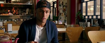 Movie still from “xXx: Return of Xander Cage” (2017), directed by D.J. Caruso – A man with a cross necklace sitting at a table in a restaurant; Close Up shot, Over the shoulder angle
