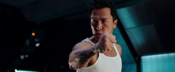 Movie still from “xXx: Return of Xander Cage” (2017), directed by D.J. Caruso – A man in a white tank top is holding something in his hand; Close Up shot, Over the shoulder angle