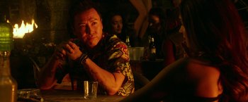 Movie still from “xXx: Return of Xander Cage” (2017), directed by D.J. Caruso – A man sitting at a table with a drink in front of him; Medium shot, Over the shoulder angle