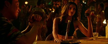 Movie still from “xXx: Return of Xander Cage” (2017), directed by D.J. Caruso – A woman sitting at a table in front of a microphone; Medium shot, Over the shoulder angle