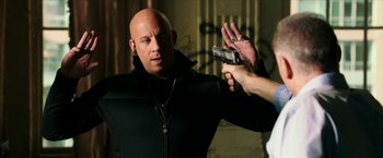 Movie still from “xXx: Return of Xander Cage” (2017), directed by D.J. Caruso – A bald man holding a gun in his hand; Medium shot, Over the shoulder angle