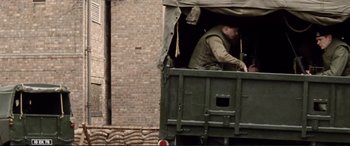 Movie still from “'71” (2014), directed by Yann Demange – A man standing in the back of an army truck; Wide shot, High angle