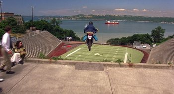 Movie still from “10 Things I Hate About You” (1999), directed by Gil Junger – A person on a motorcycle jumping over a field; Extreme Wide shot, High angle