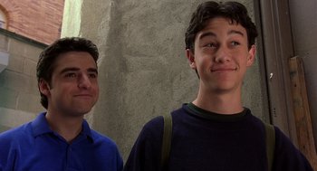 Movie still from “10 Things I Hate About You” (1999), directed by Gil Junger – Two young men standing next to each other in front of a stone wall; Close Up shot, Low angle