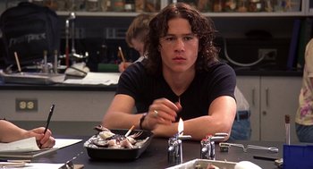 Movie still from “10 Things I Hate About You” (1999), directed by Gil Junger – A man sitting at a table with a lit candle in front of him; Medium shot, Over the shoulder angle