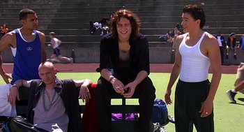 Movie still from “10 Things I Hate About You” (1999), directed by Gil Junger – A woman sitting on top of a bench next to two other people; Medium shot, Low angle