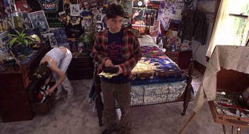 Movie still from “10 Things I Hate About You” (1999), directed by Gil Junger – A young man standing in front of a bed holding a wallet; Wide shot, High angle