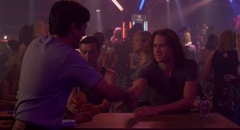 Movie still from “10 Things I Hate About You” (1999), directed by Gil Junger – A group of young men sitting at a bar shaking hands; Medium shot, Over the shoulder angle