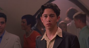 Movie still from “10 Things I Hate About You” (1999), directed by Gil Junger – A young man in a suit standing in front of a group of people; Close Up shot, Over the shoulder angle