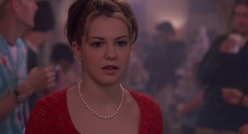 Movie still from “10 Things I Hate About You” (1999), directed by Gil Junger – A young woman wearing a red dress and a pearl necklace; Close Up shot, Over the shoulder angle