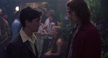Movie still from “10 Things I Hate About You” (1999), directed by Gil Junger – Two young men talking to each other in front of a group of people; Medium shot, Over the shoulder angle