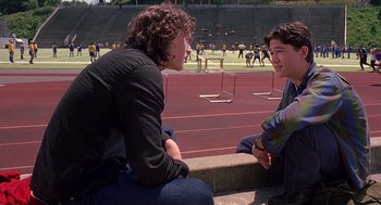 Movie still from “10 Things I Hate About You” (1999), directed by Gil Junger – Two young men are sitting on the side of a track; Medium shot, High angle