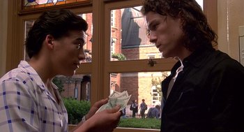 Movie still from “10 Things I Hate About You” (1999), directed by Gil Junger – Two young men looking at each other while holding money in their hands; Medium shot, Over the shoulder angle