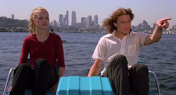 Movie still from “10 Things I Hate About You” (1999), directed by Gil Junger – A man and a woman sitting on a boat in front of a body of water; Medium shot, High angle