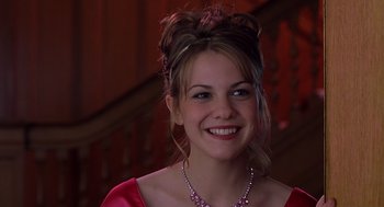 Movie still from “10 Things I Hate About You” (1999), directed by Gil Junger – A young woman wearing a red dress and a pink necklace; Close Up shot, Over the shoulder angle
