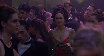 Movie still from “10 Things I Hate About You” (1999), directed by Gil Junger – A woman in a green and red dress standing in front of a group of people; Medium shot, Over the shoulder angle