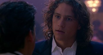 Movie still from “10 Things I Hate About You” (1999), directed by Gil Junger – A young man with long curly hair talking to another young man; Close Up shot, Over the shoulder angle