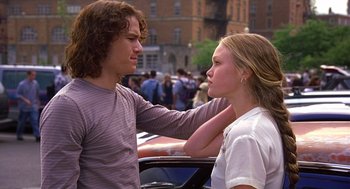 Movie still from “10 Things I Hate About You” (1999), directed by Gil Junger – A man and a woman standing next to each other in front of a car; Medium shot, Over the shoulder angle
