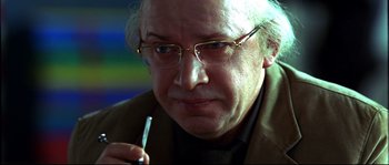 Movie still from “12” (2007), directed by Nikita Mikhalkov – An older man wearing glasses holding a cigarette; Close Up shot, Over the shoulder angle