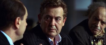 Movie still from “12” (2007), directed by Nikita Mikhalkov – A person wearing a suit and tie; Close Up shot, Over the shoulder angle