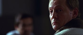 Movie still from “12” (2007), directed by Nikita Mikhalkov – An older man looking at the camera in a dark room; Close Up shot, Low angle