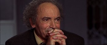 Movie still from “12” (2007), directed by Nikita Mikhalkov – An older man is sitting with his hands clasped together; Close Up shot, High angle