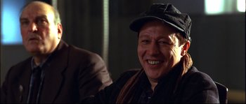 Movie still from “12” (2007), directed by Nikita Mikhalkov – A man wearing a black hat and a brown jacket; Close Up shot, Over the shoulder angle