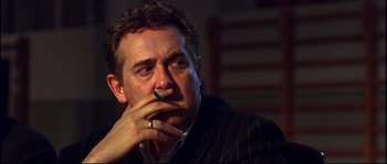 Movie still from “12” (2007), directed by Nikita Mikhalkov – A person sitting with a cigarette in his mouth; Close Up shot, Over the shoulder angle