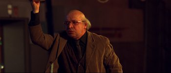 Movie still from “12” (2007), directed by Nikita Mikhalkov – An older man with a bald head and glasses; Medium shot, Low angle