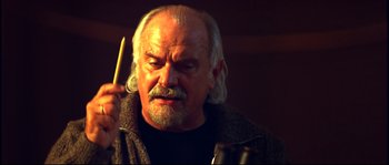 Movie still from “12” (2007), directed by Nikita Mikhalkov – An older man holding a drum stick in his hand; Close Up shot, Low angle