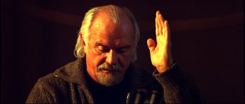 Movie still from “12” (2007), directed by Nikita Mikhalkov – An older man with white hair is holding his hand up in the air; Close Up shot, Low angle