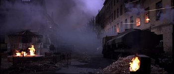 Movie still from “12” (2007), directed by Nikita Mikhalkov – Smoke billows from a building in a city; Extreme Wide shot, High angle