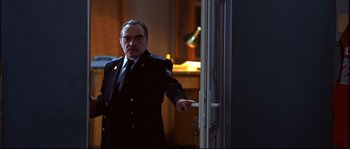 Movie still from “12” (2007), directed by Nikita Mikhalkov – A man in a uniform pointing to a door; Medium shot, Low angle