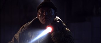 Movie still from “12” (2007), directed by Nikita Mikhalkov – A man holding a flashlight in the dark; Close Up shot, Low angle