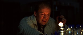 Movie still from “12” (2007), directed by Nikita Mikhalkov – An older man sitting in front of a lit candle; Close Up shot, Low angle