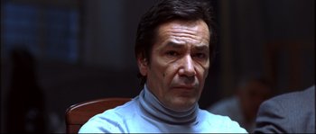 Movie still from “12” (2007), directed by Nikita Mikhalkov – A person sitting in a chair wearing a sweater; Close Up shot, Low angle