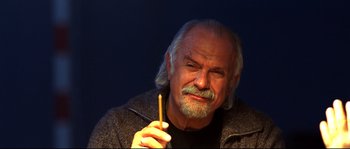Movie still from “12” (2007), directed by Nikita Mikhalkov – An older man with a long gray beard is holding a pencil; Close Up shot, Low angle